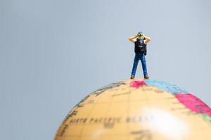 Travelers in miniature, standing on the globe and making their way to their destination, photo