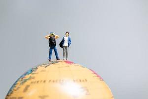 Travelers in miniature, standing on the globe and making their way to their destination, photo