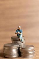 Miniature people A businessman is seated atop a mound of money photo