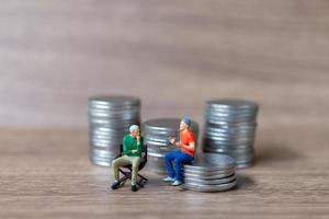 Miniature people A businessman is seated atop a mound of money photo