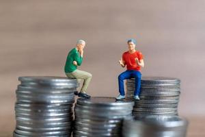 Miniature people A businessman is seated atop a mound of money photo