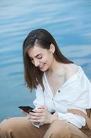 Girl outdoors texting on her mobile phone. Girl with phone. Portrait of a happy woman text sms message on her phone. photo