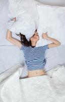 Girl sleeps in a white bed at home. Young woman sleeping in sleepwear on the white linen in bed at home, top view. photo