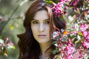 beautiful white european girl with clean skin in the park with flowering trees photo