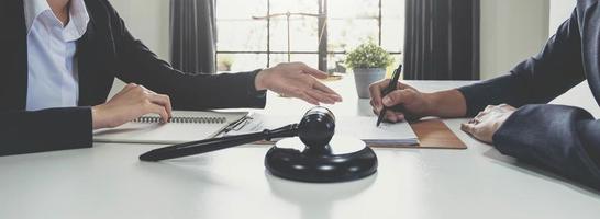 Business woman and lawyers discussing contract papers with brass scale on wooden desk in office. Law, legal services, advice, Justice concept. photo