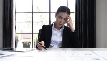 Image of an Asian woman who is tired and overthinking from working with a tablet at the office. photo