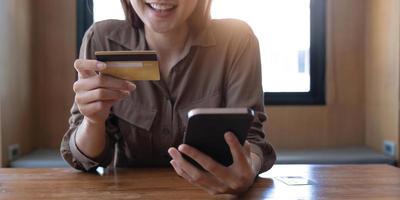 Closeup woman's hands holding a credit card and using smartphone for online shopping. photo