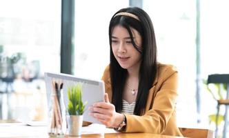 Attractive asian woman using digital tablet with pen stylus at office. photo