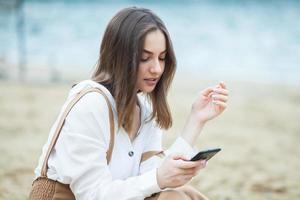 Girl outdoors texting on her mobile phone. Girl with phone. Portrait of a happy woman text sms message on her phone. photo