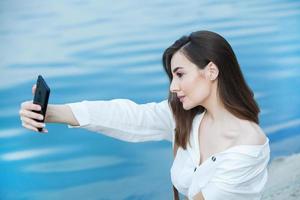 chica al aire libre enviando mensajes de texto en su teléfono móvil. chica con teléfono. retrato de un mensaje de texto de mujer feliz en su teléfono. foto