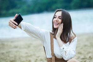 Girl outdoors texting on her mobile phone. Girl with phone. Portrait of a happy woman text sms message on her phone. photo