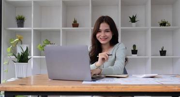 Portrait of an Asian young business Female working on a laptop computer in her workstation.Business people employee freelance online report marketing e-commerce telemarketing concept. photo