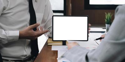 elegant attractive female office worker using mobile digital tablet with white blank screen showing report for colleague and her manager pointing to ask problem. photo