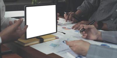 los negocios en equipo se unen para proponer ideas de trabajo tomando una tableta para tomar notas en sus escritorios en la oficina. pantalla blanca en blanco. foto