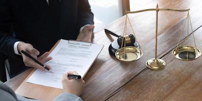 Business woman and lawyers discussing contract papers with brass scale on wooden desk in office. Law, legal services, advice, Justice concept. photo