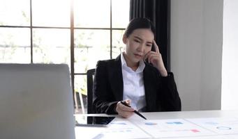 Image of an Asian woman who is tired and overthinking from working with a tablet at the office. photo