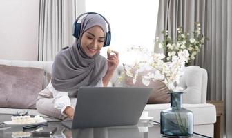 Happy Arab housewife in hijab relaxing with sweets and coffee on sofa at home enjoy indoor relaxation Relax on the comfy sofas, free space. photo