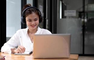 mujer joven que tiene capacitación en línea, usa una computadora portátil y auriculares inalámbricos foto