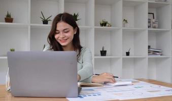 Portrait of businesswoman using laptop computer while working with using a calculator to calculate the numbers, finance accounting concept photo