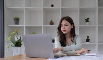 Portrait of smiling beautiful business asian woman working in modern office desk using tablet laptop computer, Business people employee freelance online marketing e-commerce telemarketing concept. photo