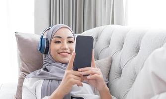 Close-up image, Attractive Muslim woman using a smartphone in living room, chatting with her friends or scrolling on online shopping website. photo