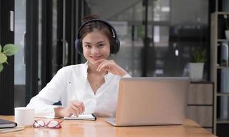 girl practicing online Use a laptop and a wireless headset. looking at camera photo