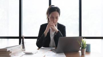 Image of an Asian woman who is tired and overthinking from working with a tablet at the office. photo