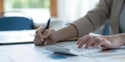 Businesswoman accountant working audit and calculating expense financial data on graph documents, doing finance in workplace. photo