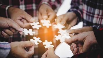 Hands holding piece of blank jigsaw puzzle for teamwork photo