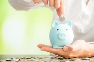 Hand putting coin in a piggy bank photo