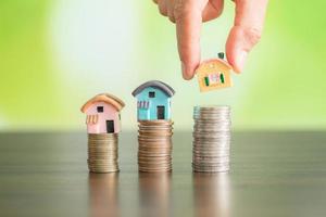 Woman hand hold a home model put on the stack coin photo