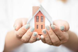 woman holding a house model with two hands photo