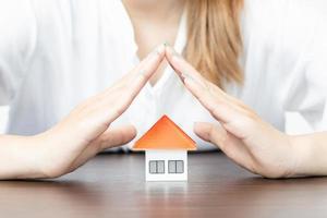 young woman use two hand to protect house model. photo