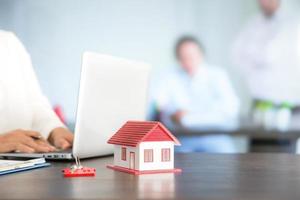 Businesswoman choosing mini house model from model on wood table photo