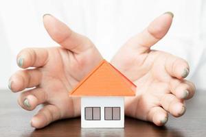 young woman use two hand to protect house model. photo