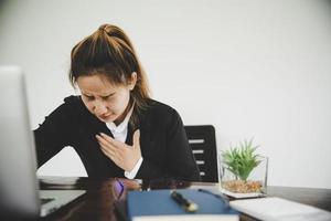 mujer de negocios asiática con traje negro está enferma de dolor en el pecho foto