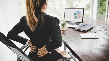 joven mujer de negocios en la oficina con terrible dolor de espalda foto