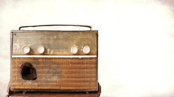 A very old, damaged radio player with an old picture background. photo