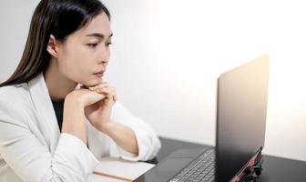 jóvenes asiáticos que sienten estrés por el trabajo, mientras están sentados frente a la computadora portátil en su casa. foto