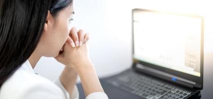 jóvenes asiáticos que sienten estrés por el trabajo, mientras están sentados frente a la computadora portátil en su casa.