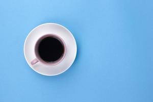 An isolated black coffee on light pink cub on light blue background photo