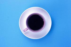 An isolated black coffee on light pink cub on blue background photo