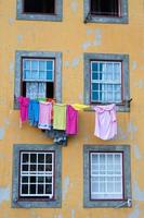 Close up of a yellow facade of an old building in Porto downtown. Colorful hanging clothes to dry photo