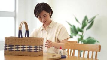 A woman making a basket with a craft band video