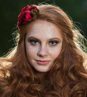 Young woman holding a bunch of yellow maple leaves. Autumn portrait of young woman. Red haired girl in autumn forest photo