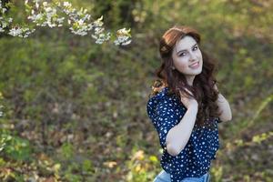 hermosa chica europea blanca con piel limpia en el parque con árboles en flor foto