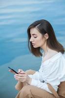 Girl outdoors texting on her mobile phone. Girl with phone. Portrait of a happy woman text sms message on her phone. photo