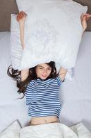 chica duerme en una cama blanca en casa. mujer joven durmiendo en ropa de dormir en el lino blanco en la cama en casa, vista superior. foto