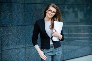 experto en negocios confiado. profesional exitoso feliz posando cerca del edificio de oficinas. chica europea. dama de negocios rusa. concepto de líder empresarial femenino. retrato de mujer de negocios exitosa foto