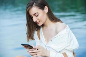 Girl outdoors texting on her mobile phone. Girl with phone. Portrait of a happy woman text sms message on her phone. photo